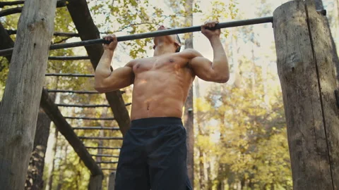 Man is doing pull ups exercises on horizontal bar. Muscular man with naked torso Stock Footage 165040539