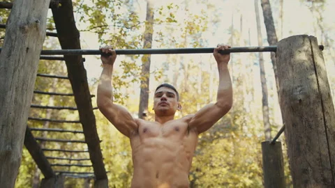 Man is doing pull ups exercises on horizontal bar. Muscular man with naked torso Stock Footage 165044122