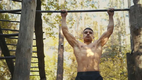 Man is doing pull ups exercises on horizontal bar. Muscular man with naked torso Stock Footage 165049508