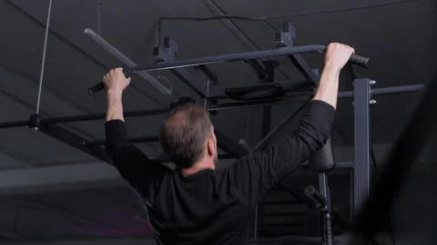 Man doing pull-ups in gym on horizontal bar, rear view Stock Footage 312065831