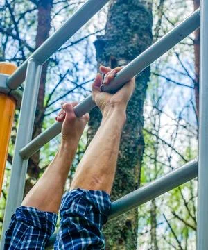 Man doing pull-ups on the horizontal bar, during workout training, outdoors. Stock Photos