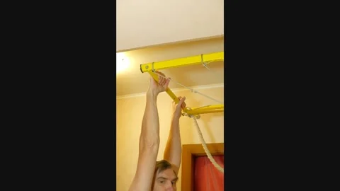 Man doing pull-ups on a wall-mounted chin-up bar at home Stock Footage 327868734