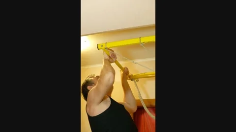 Man doing pull-ups on a wall-mounted chin-up bar at home Stock Footage 327868747