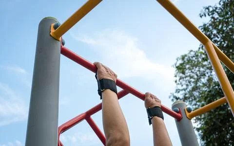 Man doing pull ups workout on the steel bar in the park. Stock Photos
