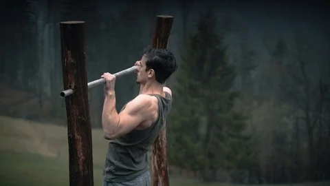 Man doing pullups on the bar with heavy rain Stock Footage 105868172