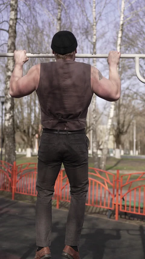 A man is doing pullups to build strength and exercise muscles at an outdoor park Vidéo 276902061