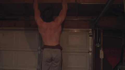 Man doing pullups on a cross beam in a garage in 4k. Stock Footage 93629911