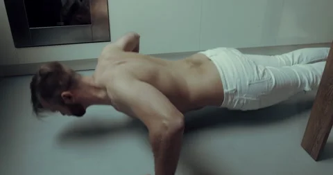 A man is doing push-ups in the apartment Stock Footage 134680092