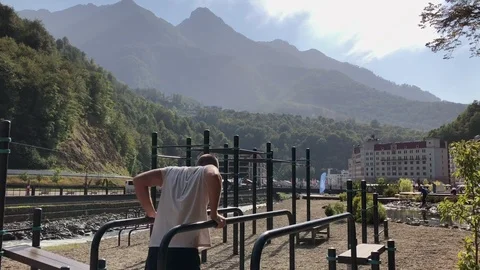 Man doing push ups on bars. Young athletic shirtless man dressed in sports Stockbeeldmateriaal 97365003