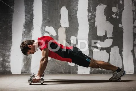 Man doing push ups on dumbbells the wall backdrop Stock Photos