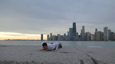 Man is doing push ups on the ebankment. Athlete training outdoors. Downtown with Video stock 82639268