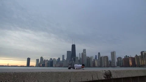 Man is doing push ups on the ebankment. Athlete training outdoors. Downtown with Video stock 82645686