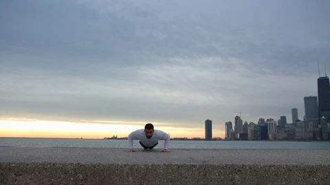 Man is doing push ups on the ebankment. Athlete training outdoors. Downtown with Vidéo 82646533