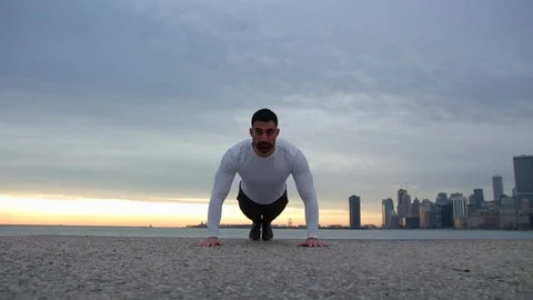 Man is doing push ups on the ebankment. Athlete training outdoors. Downtown with Stock-Footage 82647404