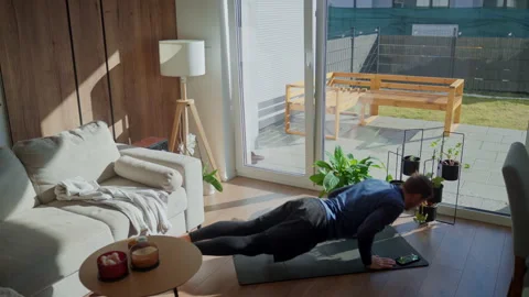 Man doing push ups on exercise mat at home in sunny living room Stock Footage 331252970