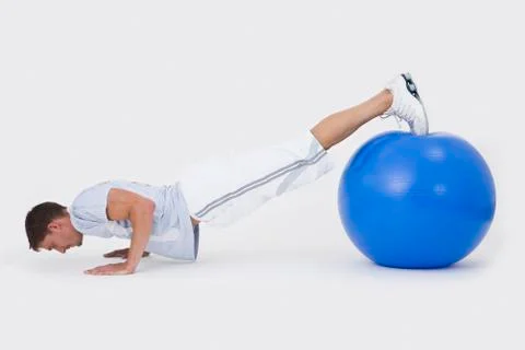A man doing push-ups with an exercise ball Stock Photos