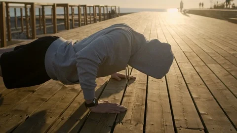 Man is doing push ups with force from wooden ground in evening 스톡 동영상 114887674