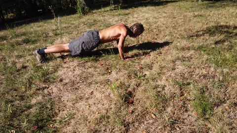 Man doing push-ups on grass fitness outdoor exercise Stock Footage 345124139