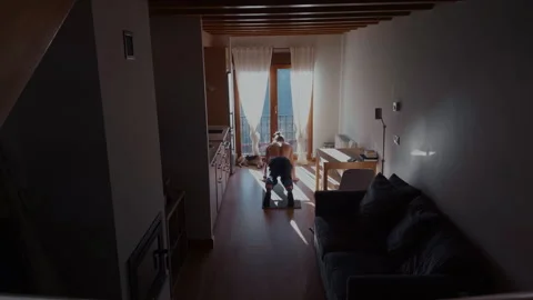 Man doing push ups at home with dog relaxing near window Stock Footage 332557602