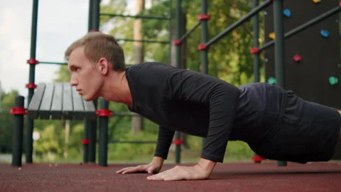 Man doing push-ups at an outdoor fitness ground. Young athletic man doing p.. Stock Footage 341729857