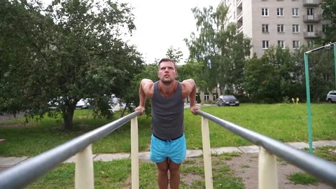 Man doing push-ups on parallel bars during street workout Stock Footage 114089627