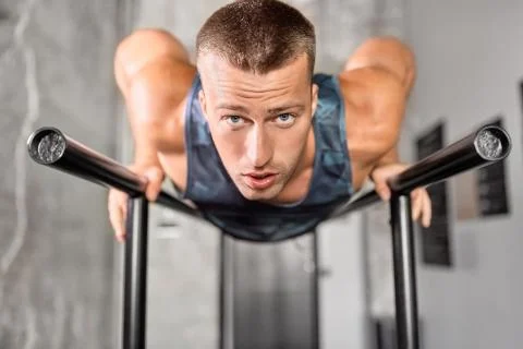 Man doing push-ups on parallel bars in gym Stock Photos