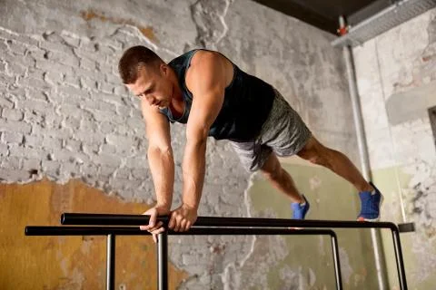 Man doing push-ups on parallel bars in gym Stock Photos
