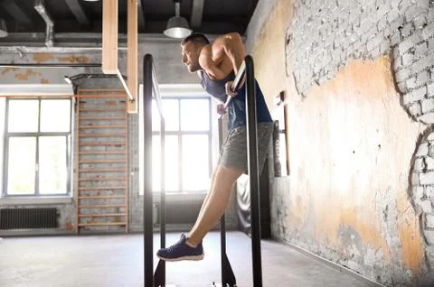Man doing push-ups on parallel bars in gym Stock Photos
