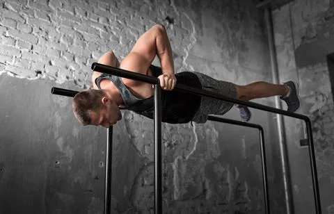 Man doing push-ups on parallel bars in gym Stock Photos