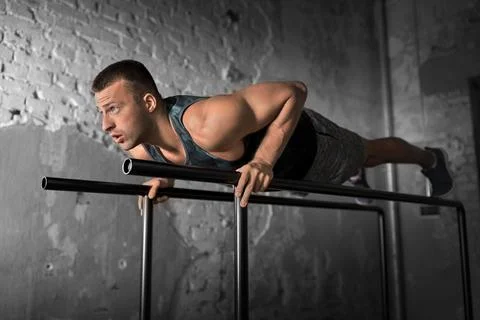Man doing push-ups on parallel bars in gym Stock Photos