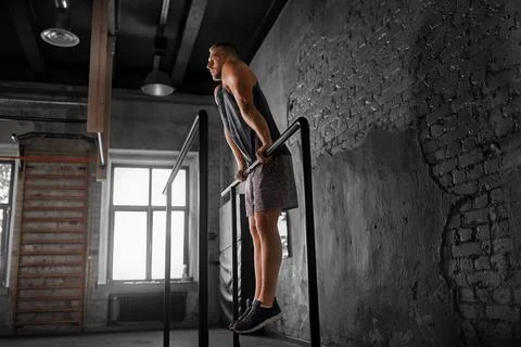 Man doing push-ups on parallel bars in gym Foto stock