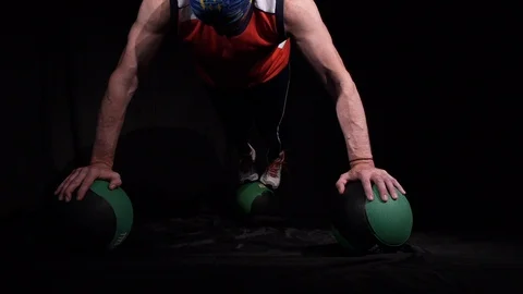 Man doing Push-ups using three medballs.Isolated on a black background. Stock Footage 125080397
