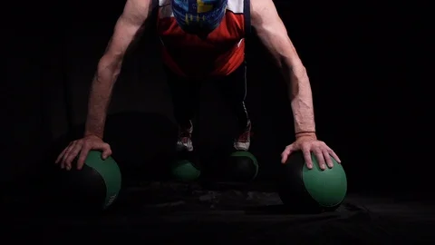 Man doing Push-ups using four medballs.Isolated on a black background. Stock Footage 125080539