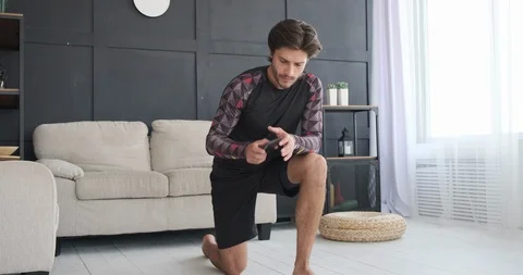 Man doing push ups while using mobile phone at home Video stock 117701498