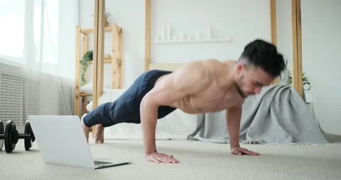 Man doing push ups while watching online tutorial using laptop Stock Footage 156520576
