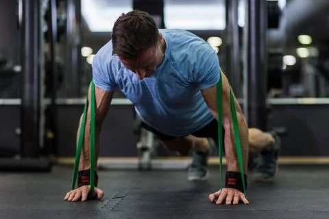 Man doing push-up using a elastic band at the gym. Stock Photos