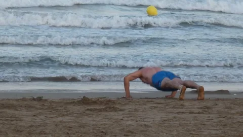 Man doing pushups on the beach by the ocean sea 動画素材 314794276