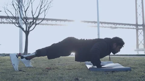 Man Doing Pushups on Grass Mat at Sunrise with Bridge and Trees in Background Vídeo Stock 313707470