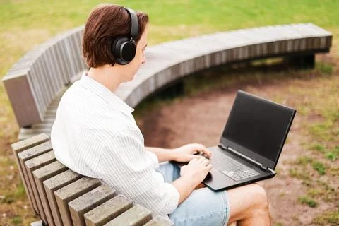 Man doing remote freelance work on a laptop while wearing headphones on a p.. Stock Photos