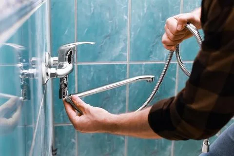 A man is doing repairs. The skilled handyman and homeowner perform a faucet.. Stock Photos