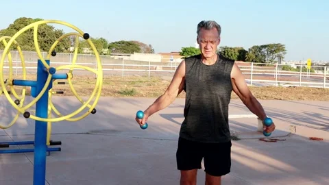 Man doing Reverse Flies at an outdoor fitness park with light dumbbells Stock Footage 284246040