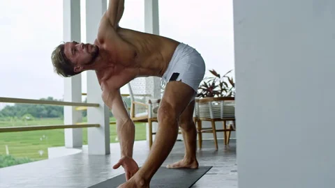 Man Doing Revolved Triangle Pose Stock Footage 92107793