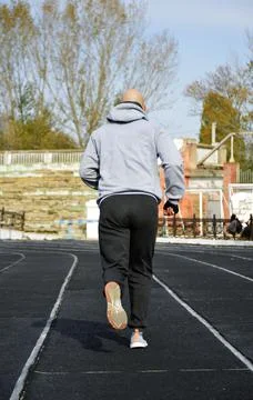 A man doing a running workout on the treadmill of the city stadium Stock Photos