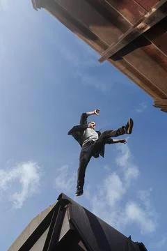 Man doing scary jump between roofs. Guy practicing parkour Stock Photos