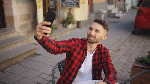 Man doing selfie uses phone sitting in cafe smile feel happy blurred background Stock Footage 92071302