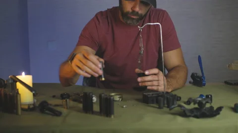 A man doing shotgun cartridges reloading with gun primers, shells, gunpowder Stock Footage 201296194