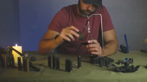 A man doing shotgun cartridges reloading with gun primers, shells, gunpowder Stock Footage 201297766
