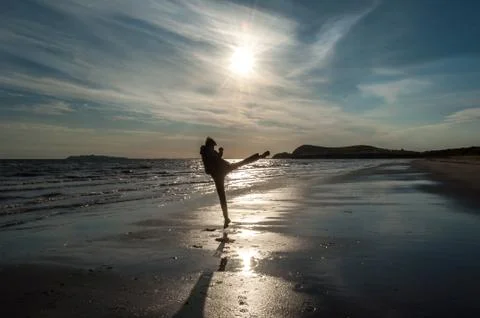 A man doing a side kick on the beach at sunrise Stock Photos