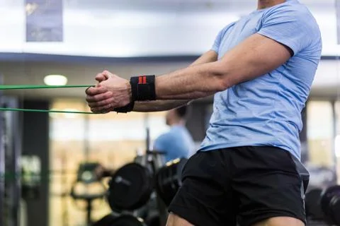 Man doing side-to-side chops exercise with elastic band at the gym. Stock Photos