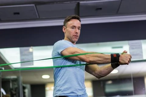 Man doing side-to-side chops exercise with elastic band at the gym. Stock Photos